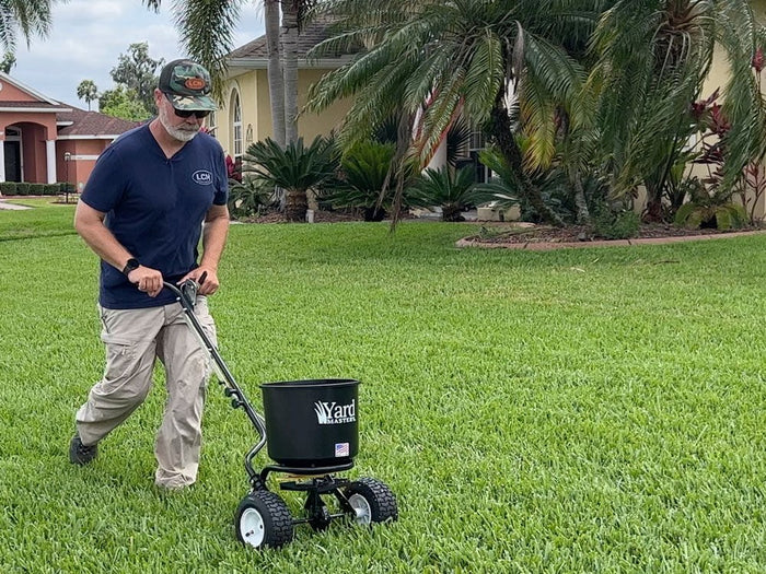 Allyn Hane spreading granular fall pre-emergent with a Yard Mastery broadcast spreader on a St. Augustine lawn